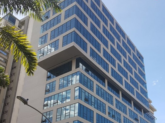 Vista em perspectiva de um edifício comercial moderno com fachada de vidro, representando a presença internacional e as unidades de negócios da Montana.